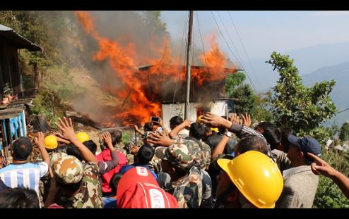 A massive fire rages in Phungling bazaar as security forces and locals look on.